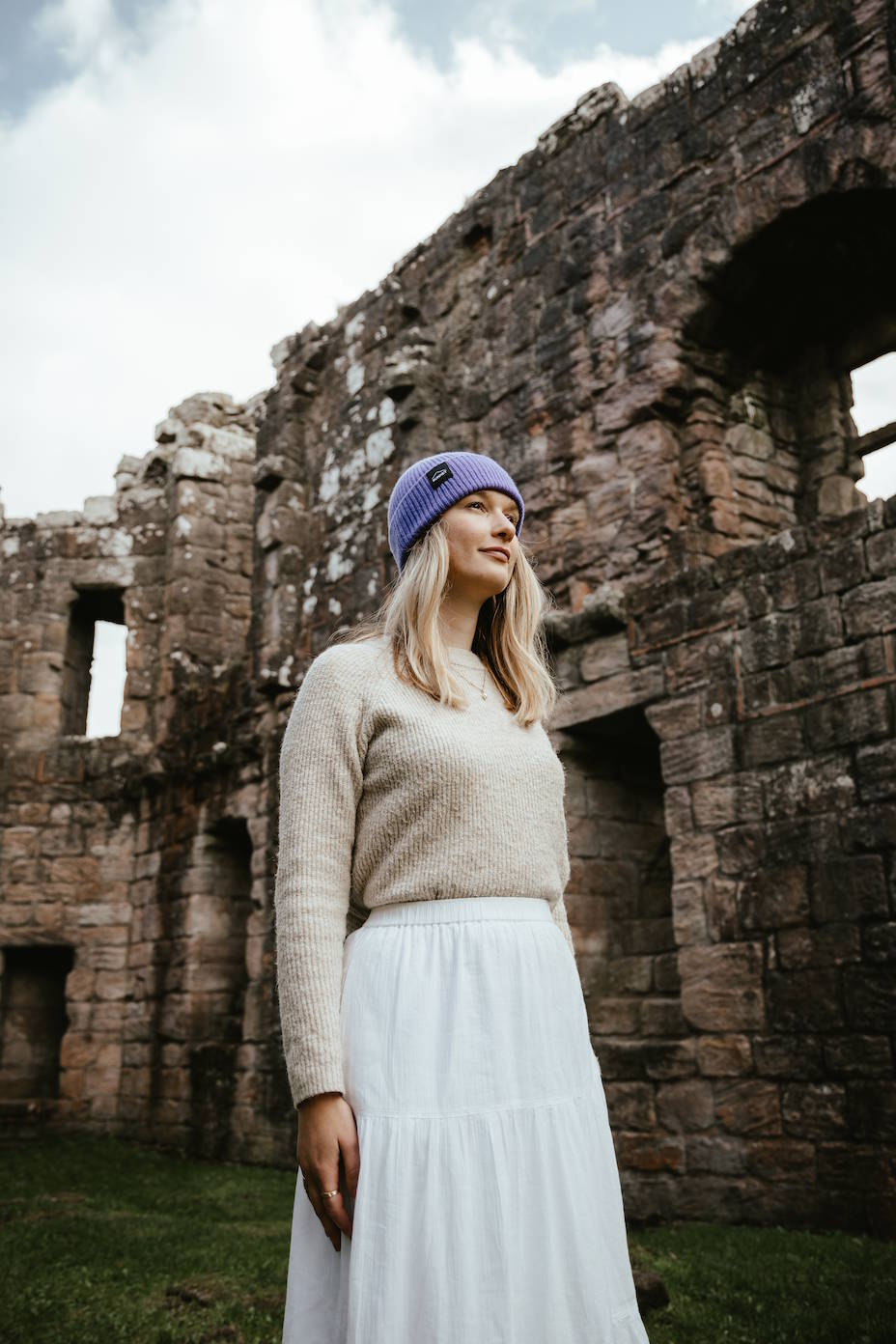 A woman in a historic castle wearing a purple Bunnet Beanie