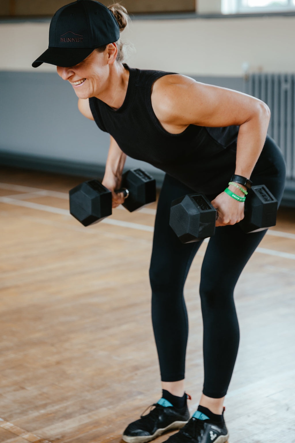 Woman exercising with dumbbells in a gym setting wearing Bunnet Cap